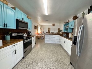 A kitchen with white cabinets, a stainless steel refrigerator, and a microwave.