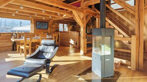 A wooden cabin interior with a dining area, a sofa, and a fireplace.