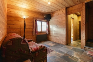 Une chambre confortable dans un chalet, avec un intérieur en bois, un lit, une télévision et une fenêtre avec des rideaux.