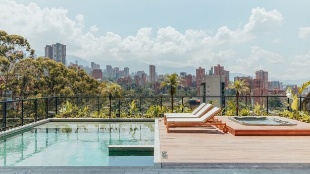 Une piscine sur le toit, dotée de chaises longues et offrant une vue sur la ville.