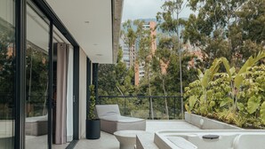 Un espace de vie extérieur moderne, doté d’un jacuzzi, de sièges et d’une porte vitrée donnant sur un balcon.