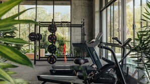 Une salle de sport équipée de tapis de course, d’un banc de musculation et d’un support pour les exercices de squat.
