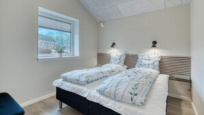 Un dormitorio con cama, lámparas de noche, una ventana y vista a un edificio.