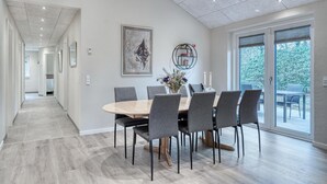 Un comedor moderno con una mesa redonda, sillas grises y un ventanal con vistas al verdor.