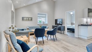 Una sala de estar moderna con un sofá, sillas, un televisor y un comedor.