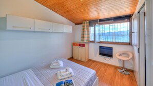 Un dormitorio con techo de madera, cama con cubierta acolchada, televisor montado en la pared y ventana con cortinas.