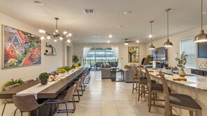 Une cuisine moderne dotée d’une longue table à manger, de sièges de bar et d’un grand îlot central avec un évier.