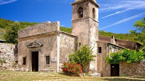 A historic building with a bell tower, stone walls, and a small entrance.