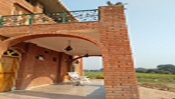 A brick building with a covered walkway and a large archway. - Lalita Home Stay (Rajnagar)