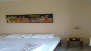 A bedroom with a bed, a nightstand, and a wall-mounted painting. - Lalita Home Stay (Rajnagar)
