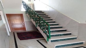 A staircase with a green handrail and marble steps leading to a wooden door. - Lalita Home Stay (Rajnagar)