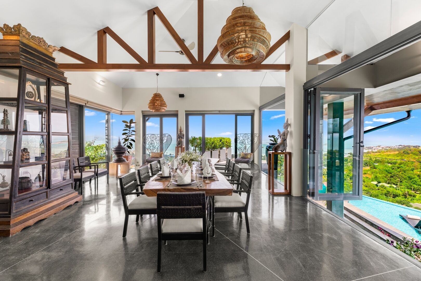 A modern dining area with a large table, chairs, and a view of the landscape.