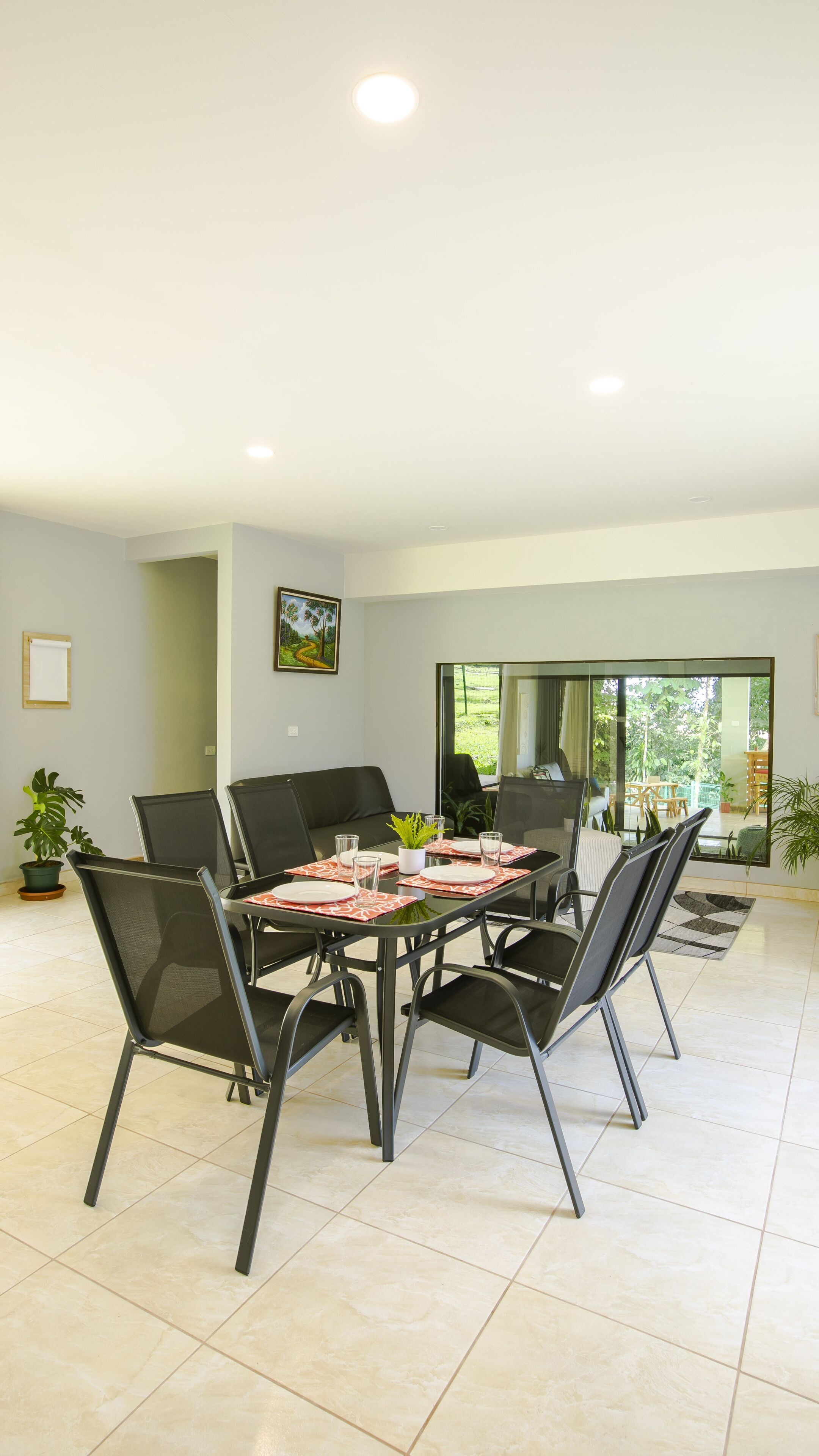 A modern dining area with a glass table, metal chairs, and a view of the outdoors.