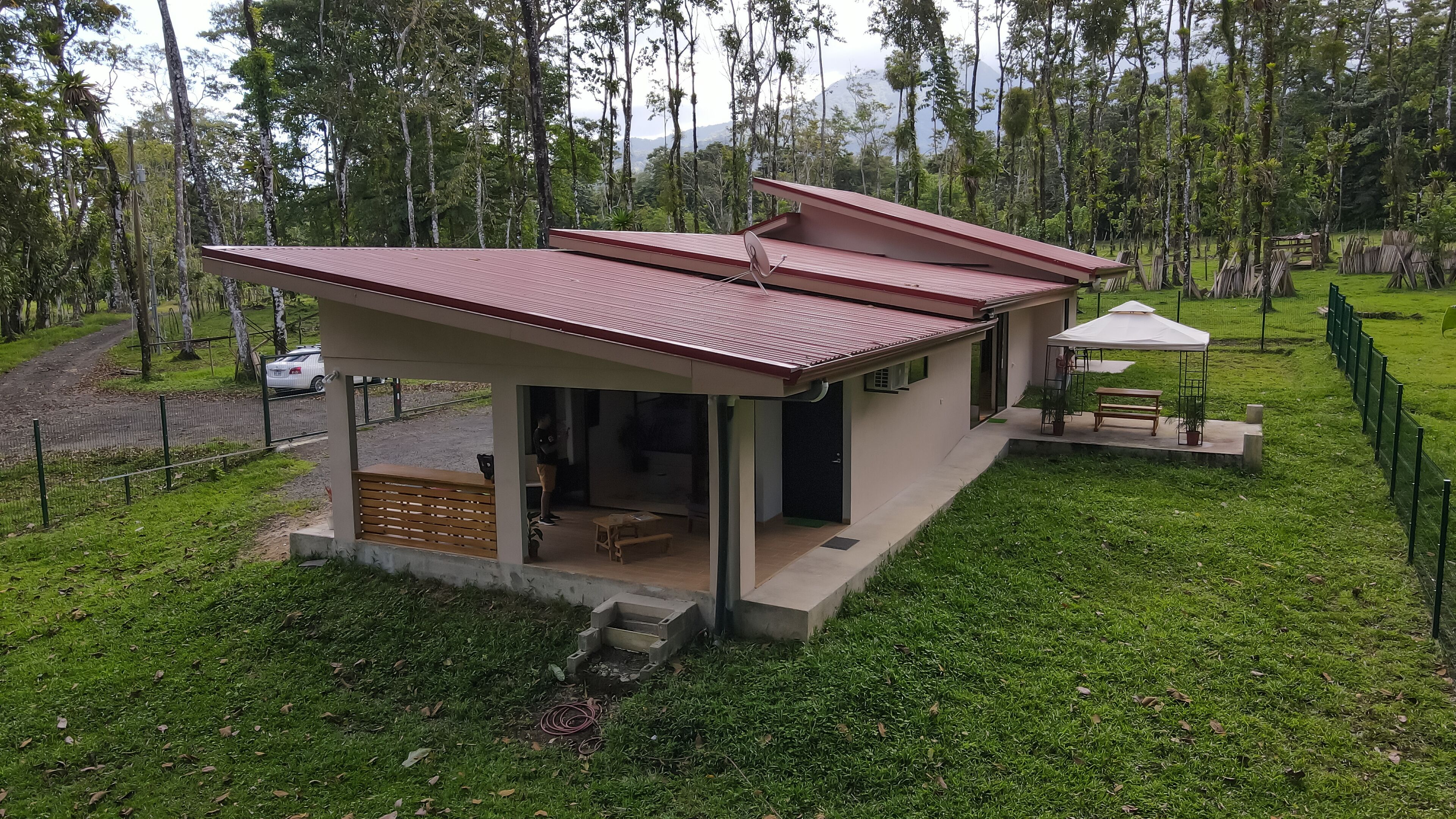 A modern, single-story house with a flat roof, a covered patio, and a small garden area.