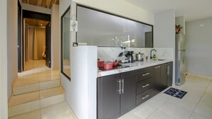 A modern kitchen with a large mirror, dark cabinets, and a stainless steel refrigerator. - River Paradise Villa (La Fortuna)