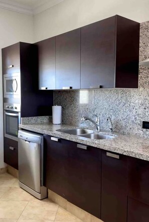 Eine moderne Küche mit dunklen Schränken, Granit-Arbeitsplatten, Edelstahlgeräten und einer Spüle.
