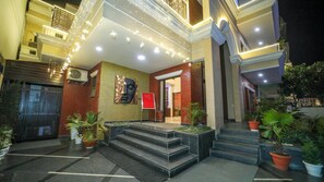 A hotel entrance with a modern design, featuring a large wall mural, a welcoming sign, and a staircase leading to the entrance. - Florence By NStay (Gurugram)