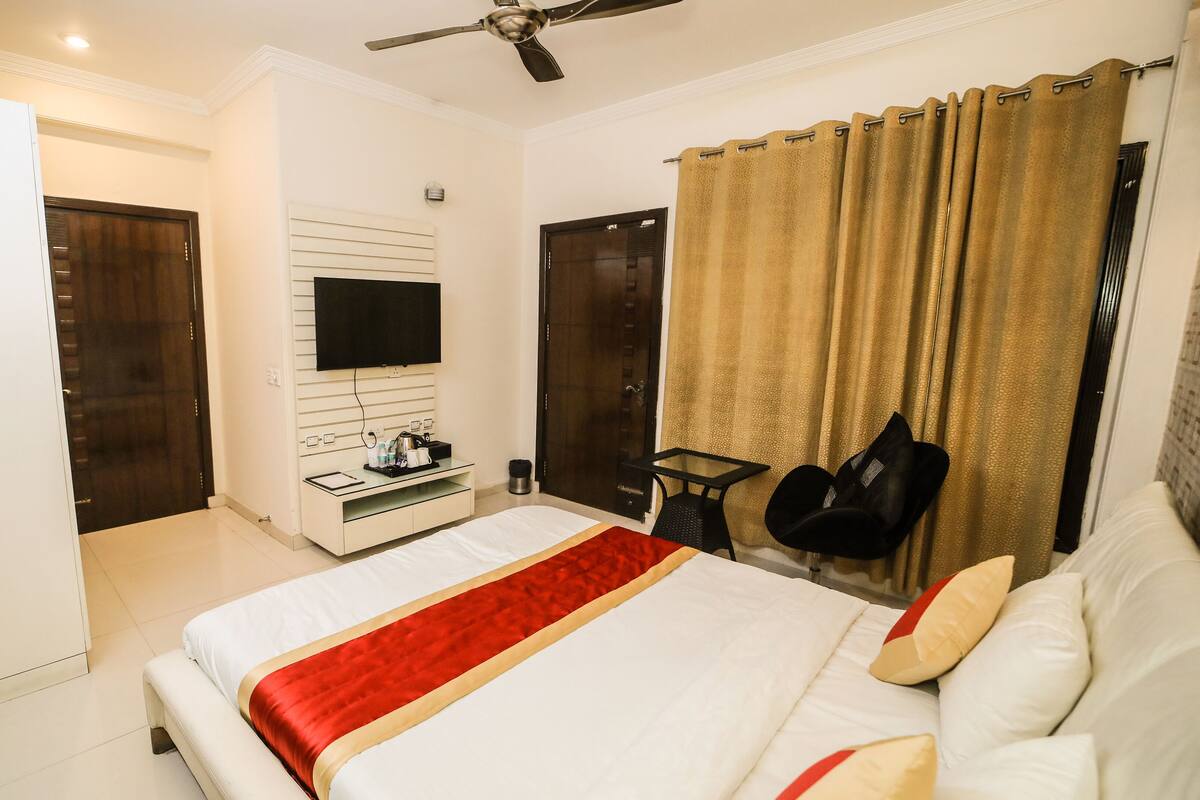 A hotel room with a bed, a TV, a desk, and a chair.