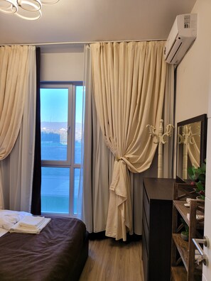Enjoy a scenic view of the water from this room, featuring a comfortable bed, dresser, and plant.