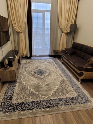 Relax in this stylish living room with a tufted sofa, wooden side table, and flat-screen TV.