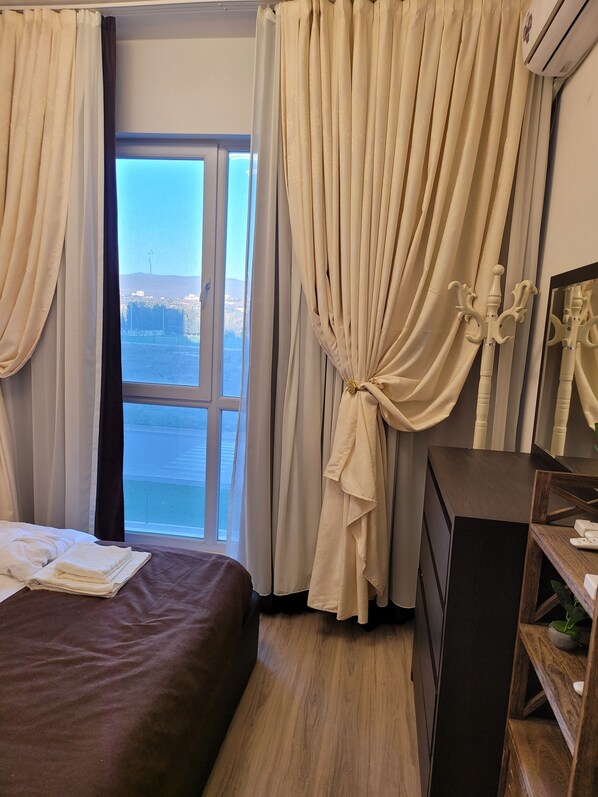 Enjoy a serene view of the water from this room's large window, featuring a comfortable bed and stylish furnishings.