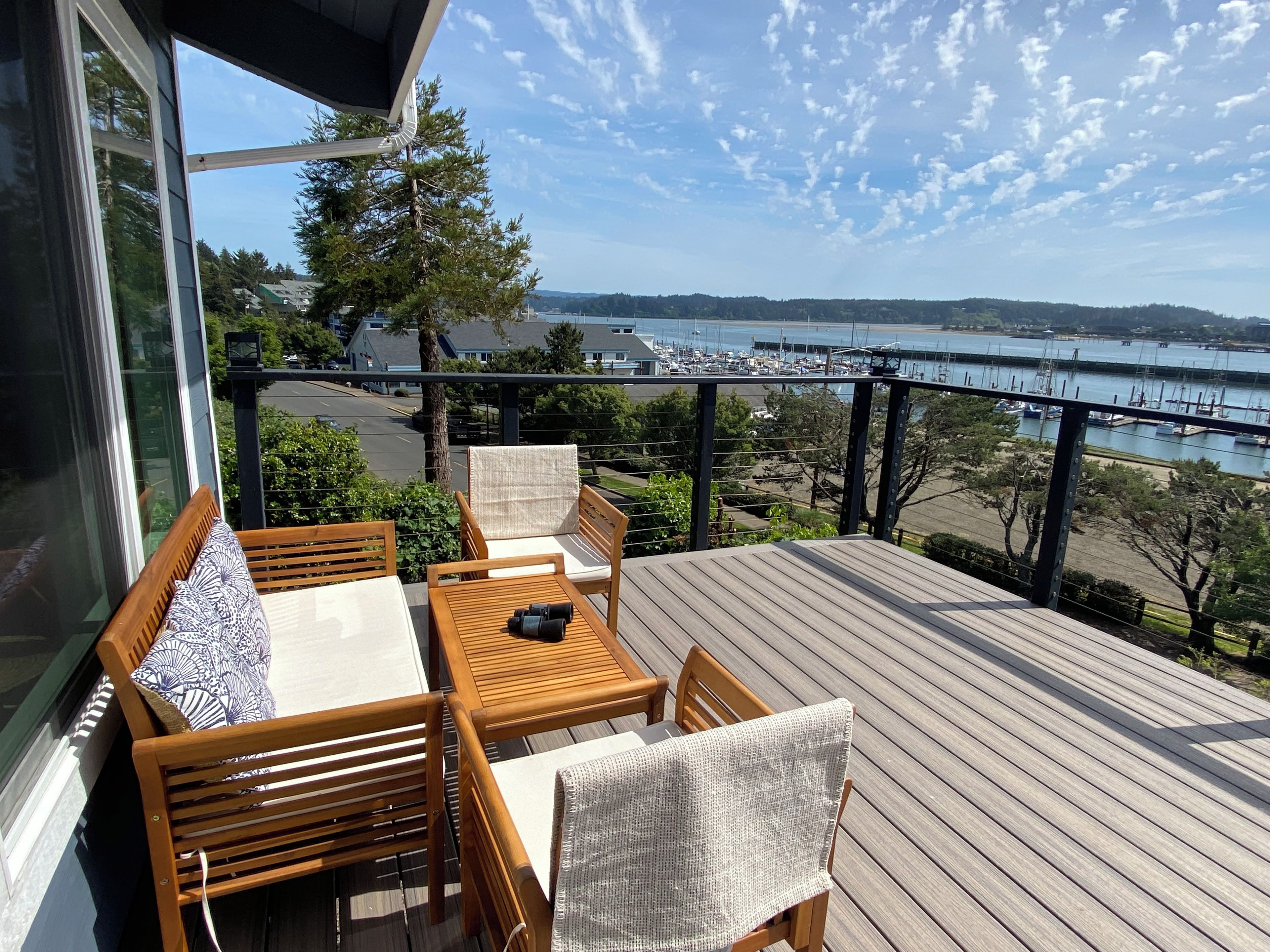 A deck with a table and chairs, overlooking a marina with boats.