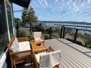 A deck with a table and chairs, overlooking a marina with boats.
