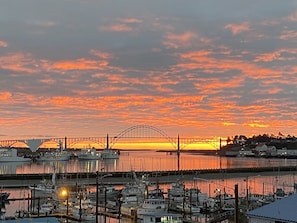 A marina with boats docked, a bridge in the background, and a sunset sky. - You're on top of Newport Harbor and the world with sights, sounds, food and fun! (Newport)