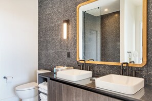 Une salle de bain moderne avec deux lavabos, un grand miroir et des toilettes.