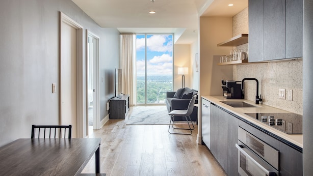 A modern kitchen with a large window, a dining area with a table and chairs, and a view of the outdoors. - City Limits by AvantStay (Austin)