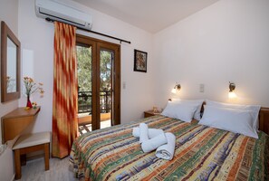 Un dormitorio con cama, escritorio, silla, ventana con cortina y un cuadro en la pared.