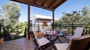 Un espacio al aire libre techado con una mesa dispuesta para comer, sillas y vistas a un edificio y árboles.