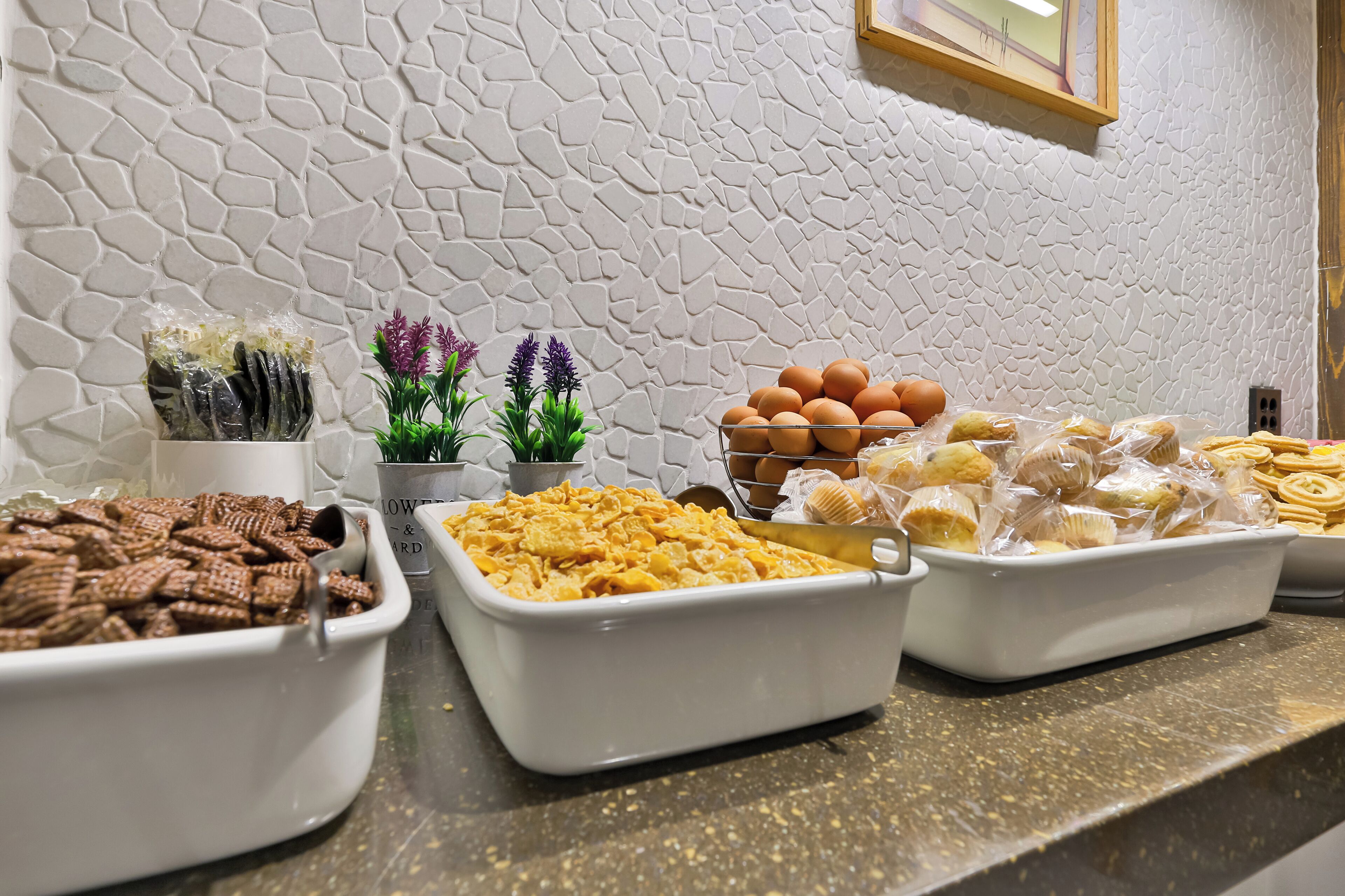 Un bufé con diversas opciones de comida, entre ellas galletas, macarons y huevos.