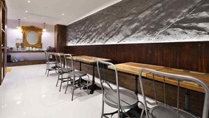 Un ristorante moderno con un lungo bancone in legno e sedie metalliche.