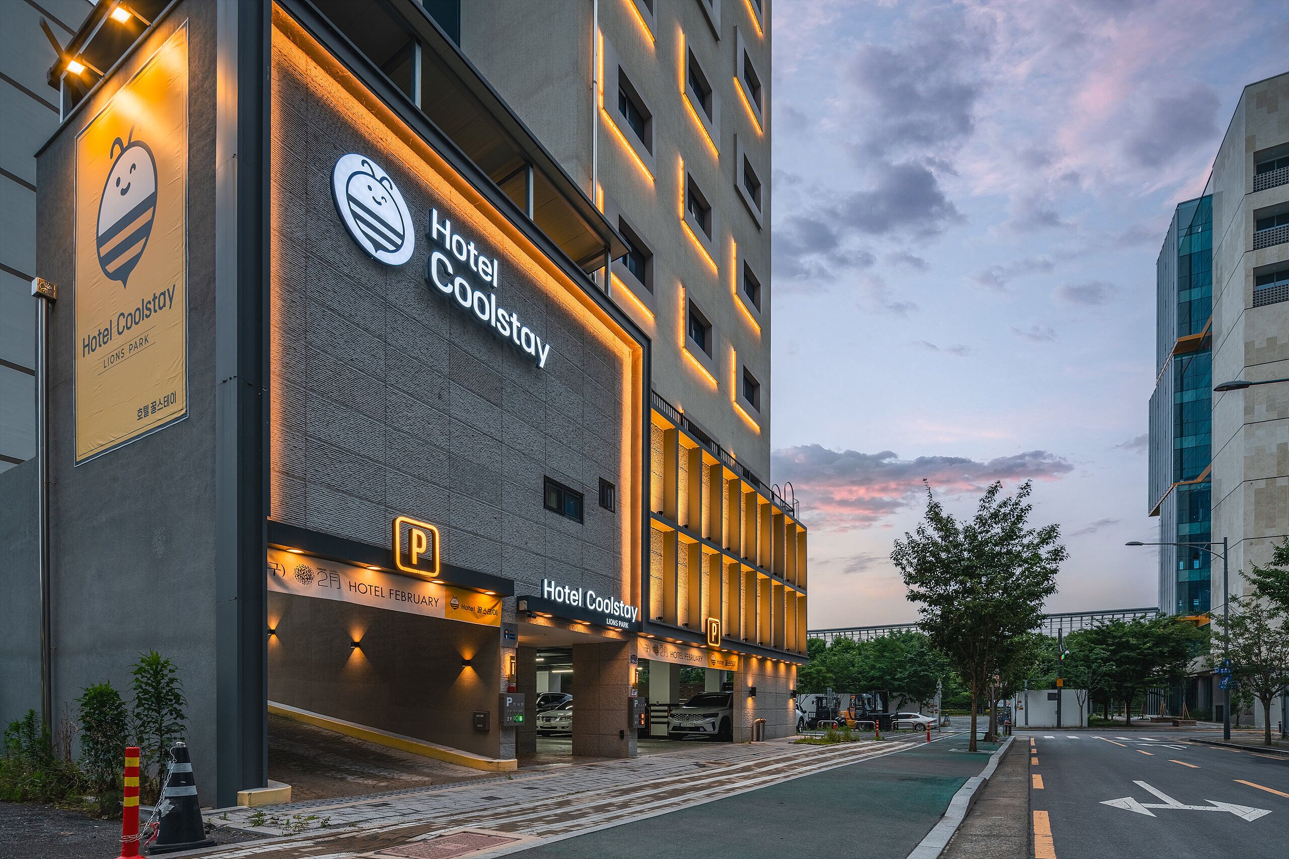 Un hotel con un letrero llamativo, un área de estacionamiento y cielo despejado.