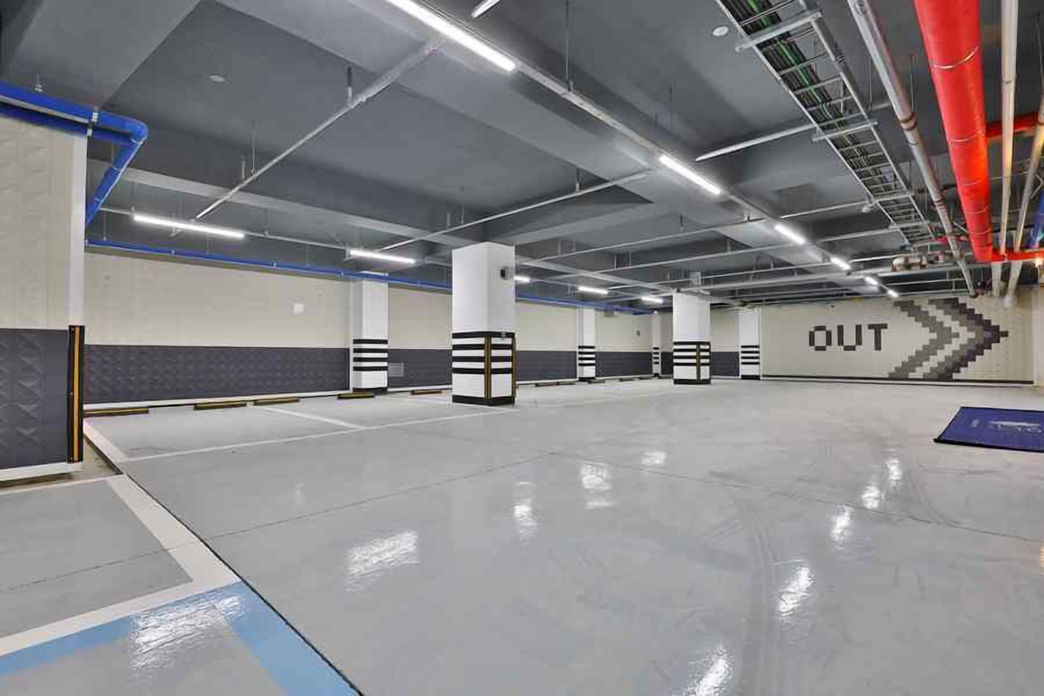 A spacious indoor parking area with clear signage, including an 'OUT' direction sign, and a clean, well-lit environment.