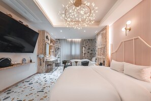 A modern hotel room with a large bed, a desk with a chair, a television, and a chandelier. - Hotel Coolstay Lions Park Previously Daegu February Lions Park (Daegu)