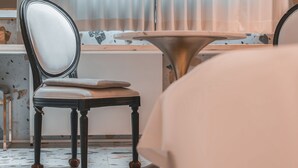 Una sedia, uno specchio, un tavolo rotondo e una finestra con tende.
