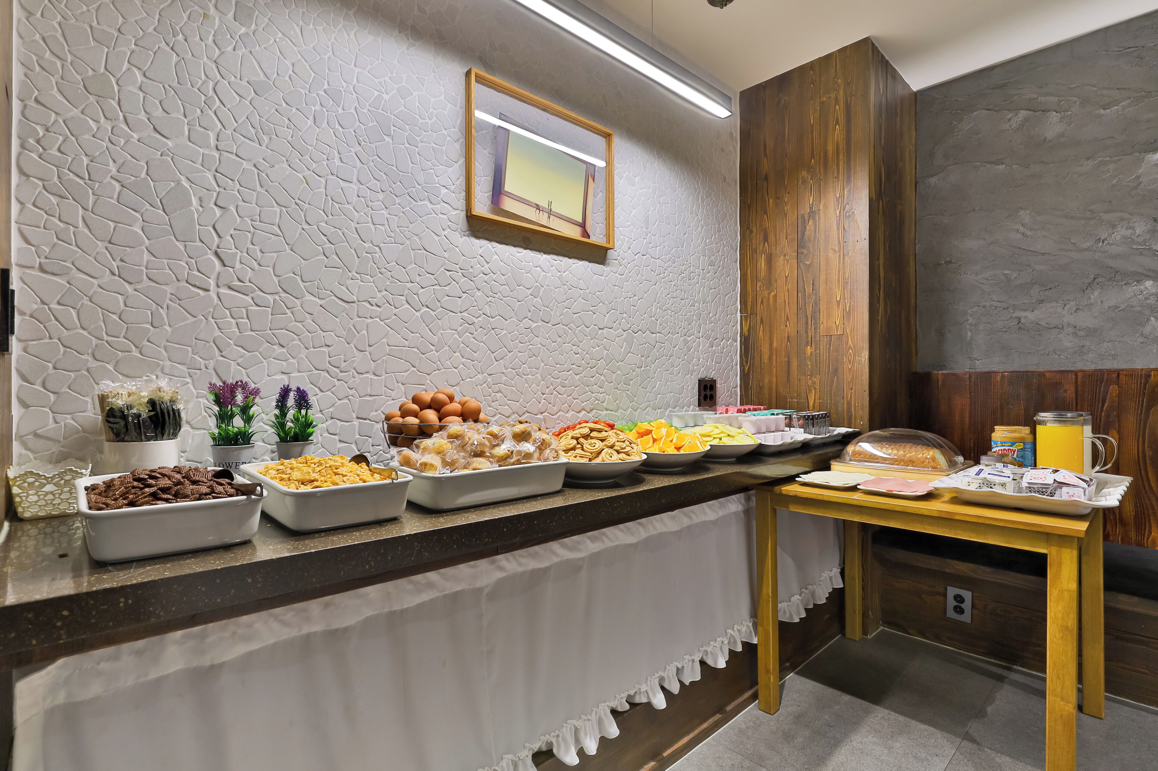 A breakfast buffet with various food items and a wooden cabinet.