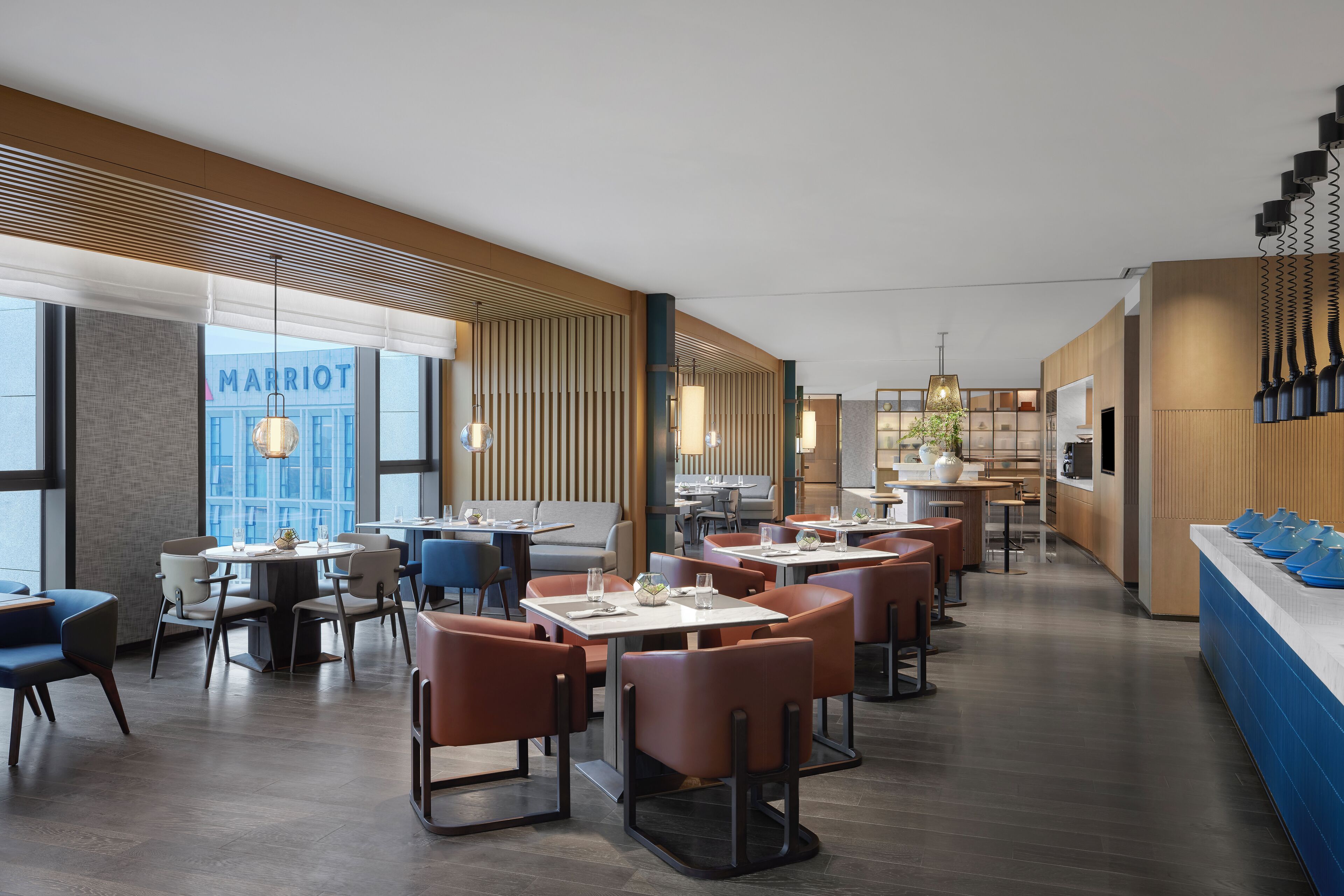 Eine moderne Hotelhalle mit verschiedenen Sitzbereichen, einem gut sichtbaren 'MARRIOT'-Schild und einer Rezeption.