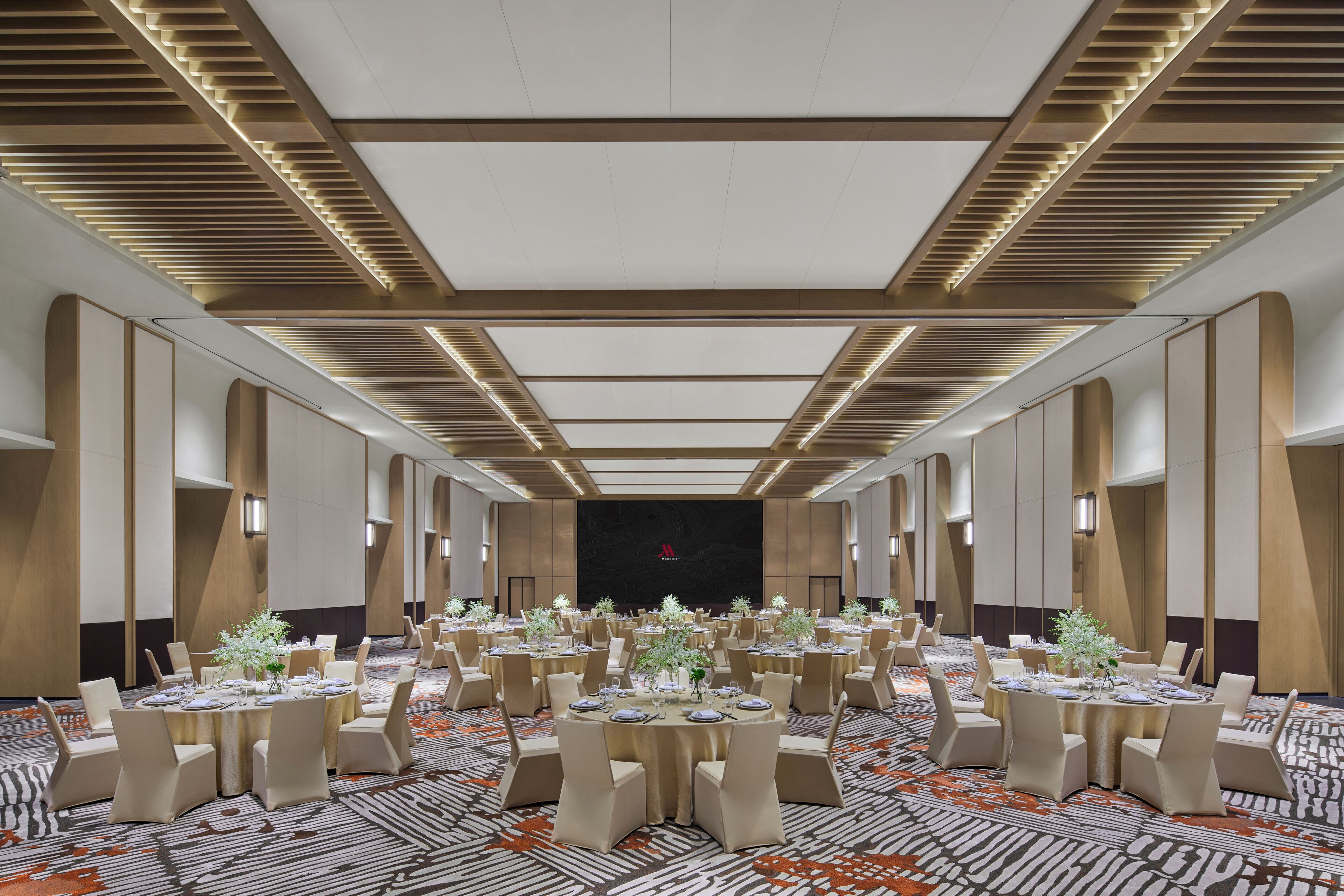 A spacious banquet hall with multiple round tables, each set with chairs and centerpieces.