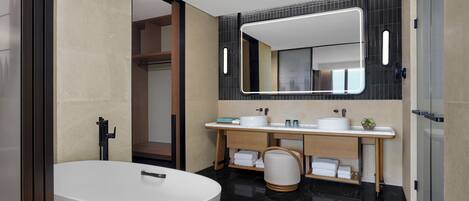A modern bathroom with a freestanding bathtub, a vanity with a mirror, and a toilet.