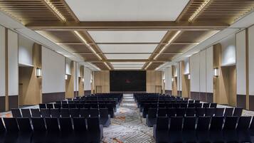 A conference room with rows of chairs, a patterned carpet, and a modern ceiling design.