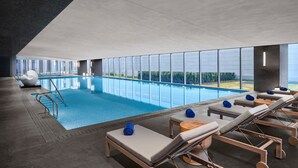 An indoor swimming pool with lounge chairs and a view of the outdoors. - Nantong Marriott (Nantong)
