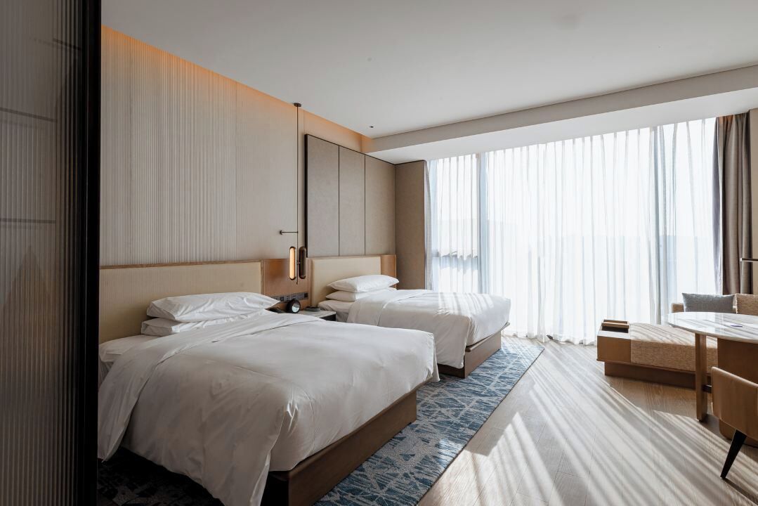 Habitación de hotel con dos camas, un escritorio y una silla.