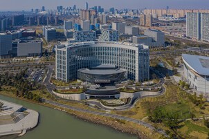 Un hotel moderno con un patio central circular, rodeado de estacionamiento y un río.