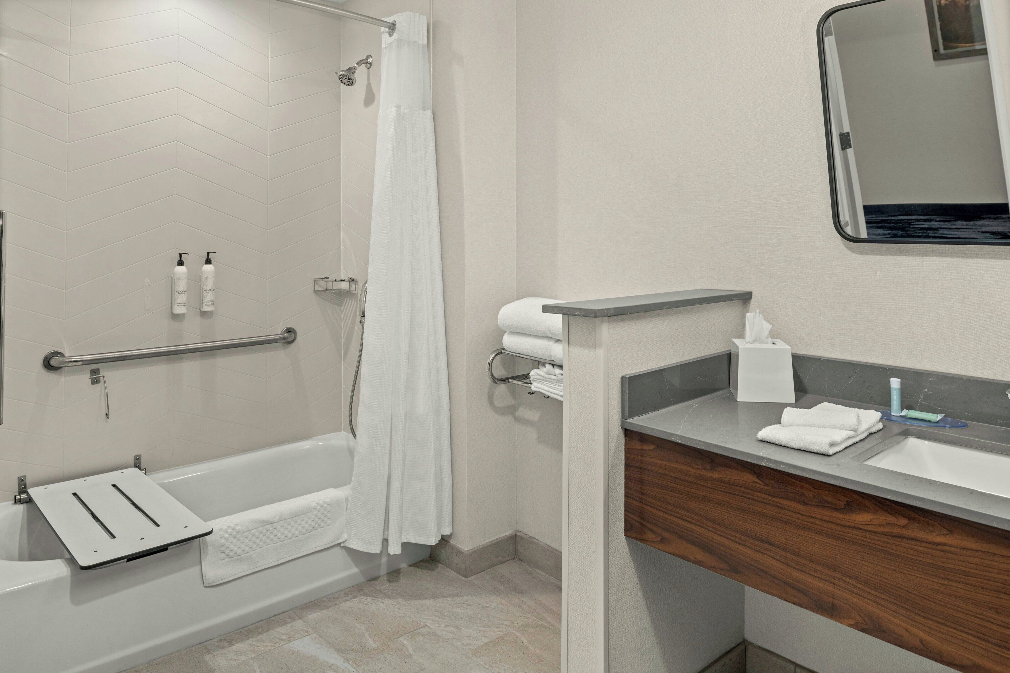 A modern bathroom with a bathtub, shower, and vanity.