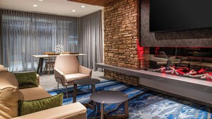 Un salon moderne avec un mur d’accent en pierre, un téléviseur à écran plat et un espace détente comprenant des canapés et une table basse.