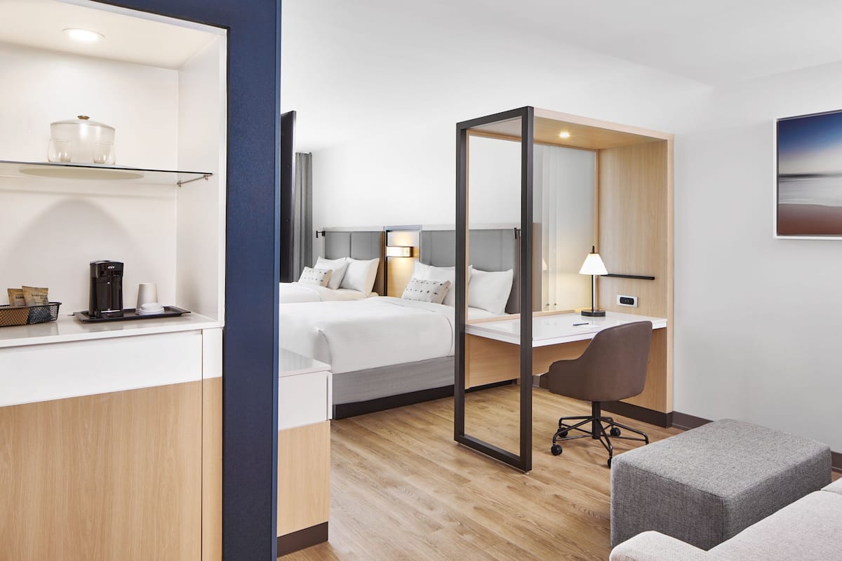 Ein Hotelzimmer mit Bett, Schreibtisch, Stuhl und einem großen Spiegel.