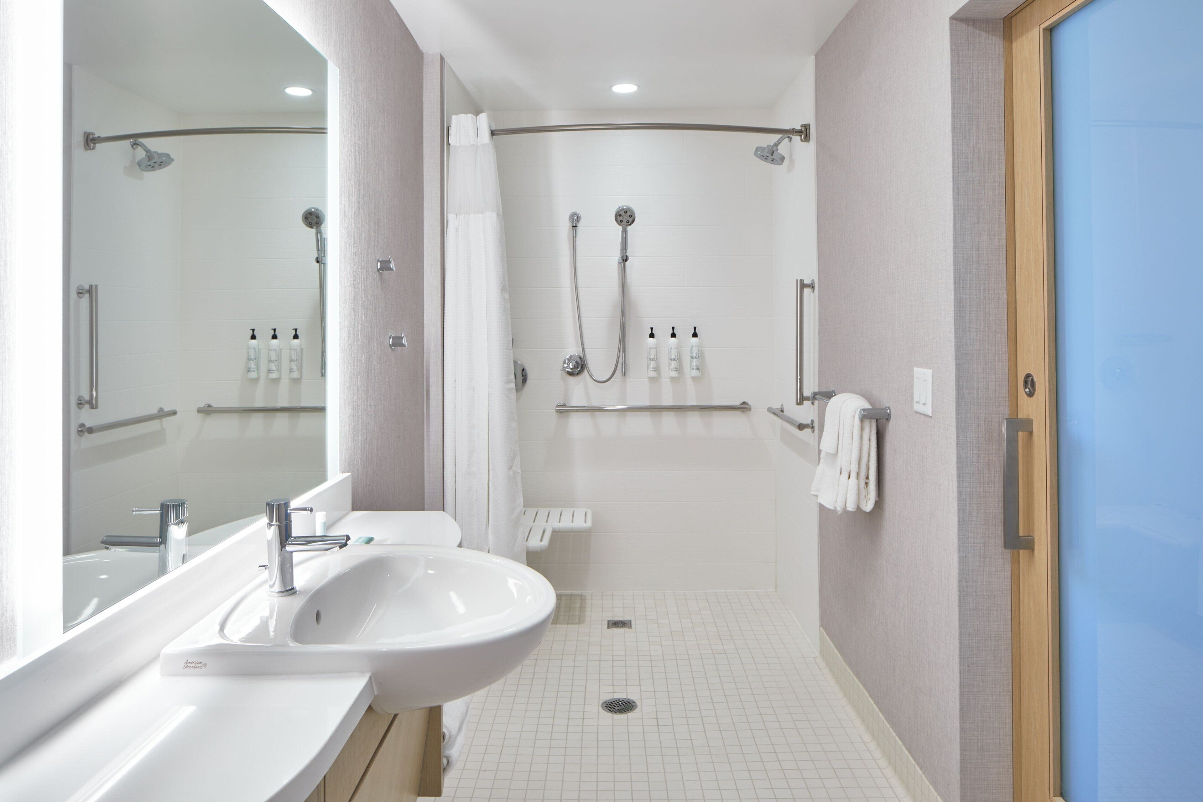 Un baño moderno con cabina de ducha, tocador doble y espejo.